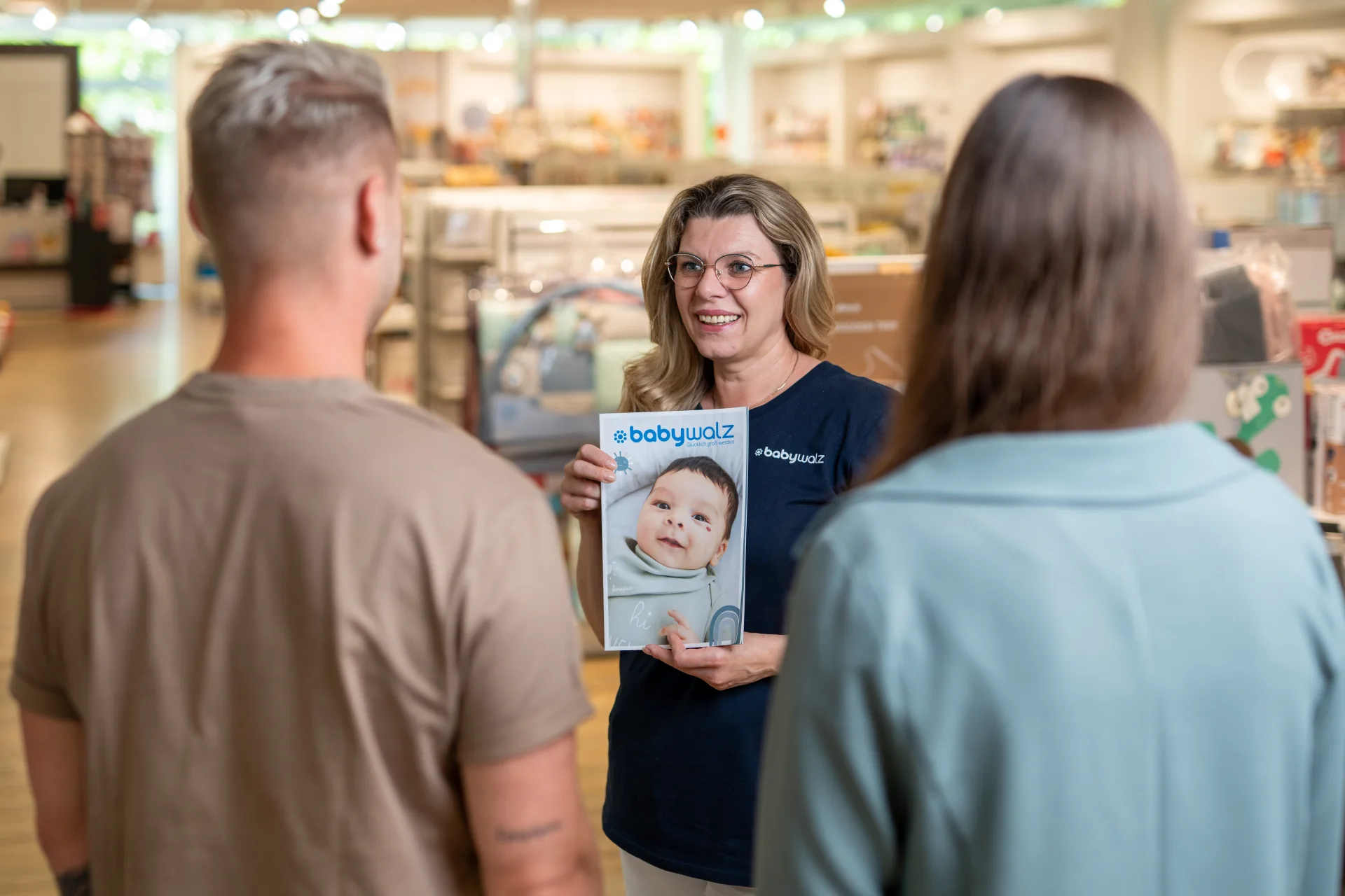baby-walz Mitarbeiterin zeigt einem Paar einen Katalog